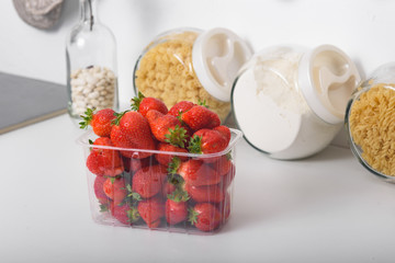 Fresh Organic Strawberries In A Plastic Box In The Kitchen. delivery of organic products. packaging of organic strawberries.