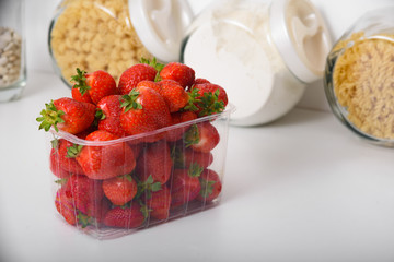 Fresh Organic Strawberries In A Plastic Box In The Kitchen. delivery of organic products. packaging of organic strawberries.