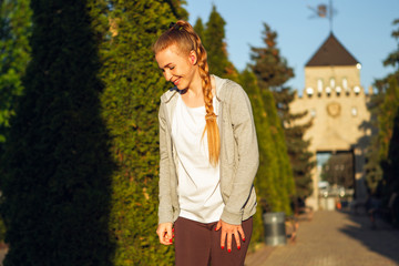 Young female runner, athlete resting after jogging in the city street in spring sunshine. Beautiful caucasian woman, fit and cheerful. Concept of sport, healthy lifestyle, movement, activity.