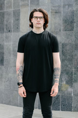 Handsome male model with beard wearing black blank t-shirt with free space for your logo or design in casual urban style