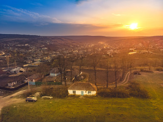 Fototapeta premium An old house on the edge of the village and a beautiful sunset. Aerial view