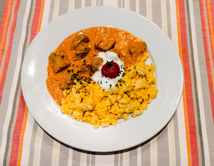 Traditional hungarian veal stew with homemade egg spaetzle on a simple table cloth.