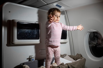 violation of safety rules in an airplane. danger. cute little toddler is fallng from baby bassinet...