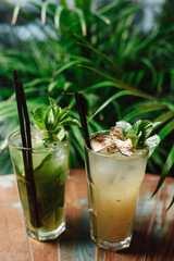 Fresh summer cold green lemonade or coctail decorated with mint on a wooden table. Green leaves on the background