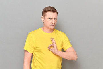 Portrait of serious confident mature man showing okay gesture