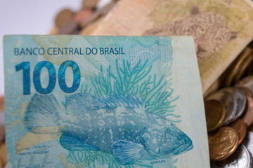 Dinheiro celulose e moedas brasileiras , notas de cem e cinquenta reais em fundo branco