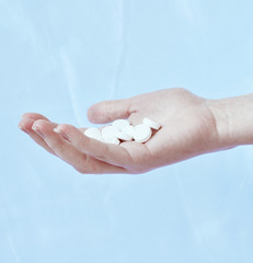White pills fall in hand