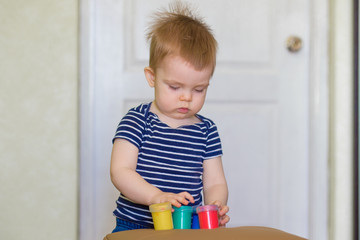 Close up of child's hands playing with colorful paints at the table. Toddler having fun and building out of bright constructor bricks. Early learning. stripe background. Developing toys