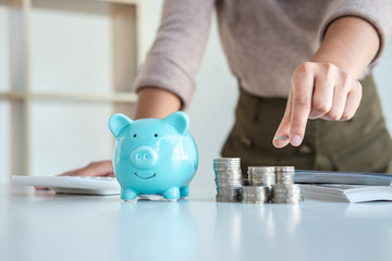 Young woman putting coins into piggy bank planning growing saving to strategy with money box for...