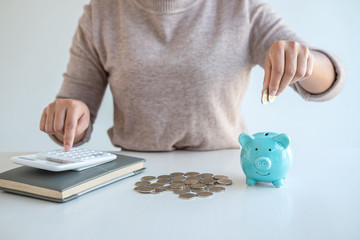 Young woman putting coins into piggy bank planning growing saving to strategy with money box for...