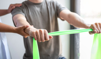 Doctor or Physiotherapist working examining treating injured arm of athlete male patient,...