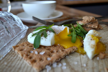Poached egg on a whole grain bread with arugula on a wooden table. Tasty and healthy breakfast.