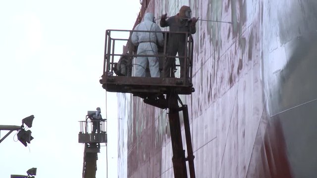 worker painting ship in shipyard drydock
