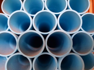 stack of long uncut blue pvc pipes on a shelf in a warehouse 