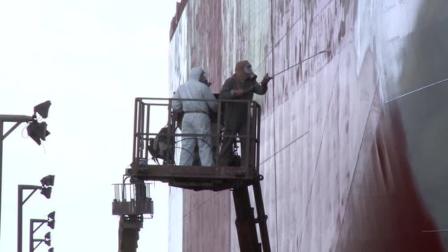 worker painting ship in shipyard drydock
