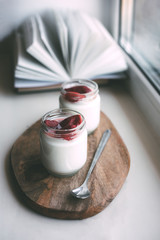 Two jars of yogurt on a wooden stand