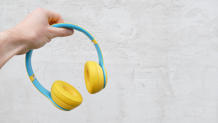 hand holding music wireless bluetooth noise cancelling yellow color headphones for learning on...
