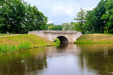 Fototapeta na wymiar Stone arch bridge across a lake in Gatchina, Russia