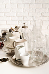 ceramic and glass cups and tableware on the table on white brick wall background