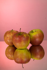 Fototapeta na wymiar Three red apples on mirroring table on mirror red background with reflection isolated close up