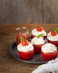 Homemade unsweetened savory appetizer cupcakes snacks with cream cheese frosting, tomato and fresh...