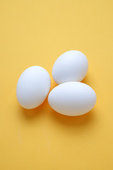 Eggs,Three White egg on the yellow background in center,Copy space for the ads