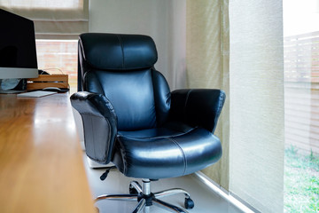 Black working chair near window at home working space with blurred table foreground.Working from home to avoid corona virus.Social distancing and stays at home safe from COVID-19 infection.