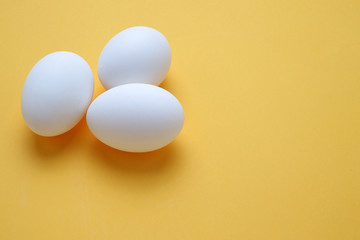 Eggs,Three White egg on the yellow background in center,Copy space for the ads