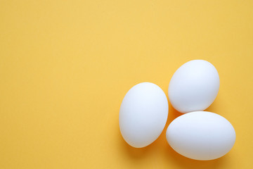 Eggs,Three White egg on the yellow background in center,Copy space for the ads