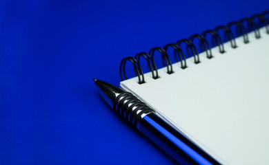 
Notebook and blue pen on a blue background. Composition blue on blue.