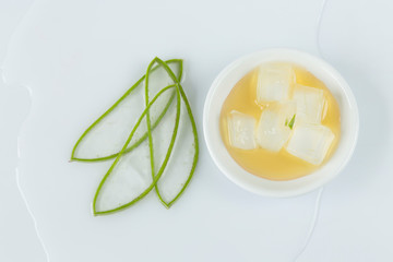 aloe vera leaves cut into thin slices, bowl with honey and pieces of aloe vera on white background