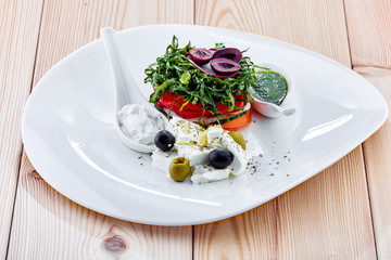 A plate of food with a vegetable salad with feta cheese