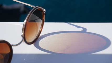 Fototapeta na wymiar Fashion round sunglasses on sea beach under clear blue sky. Summer holiday relax background