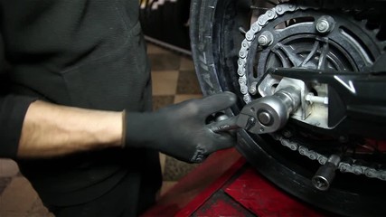 mechanic tightens screw on a motorcycle - Powered by Adobe