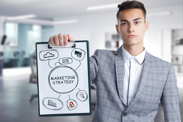 Business, Technology, Internet and network concept. Young businessman working on a virtual screen of the future and sees the inscription: marketing strategy