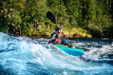 Extreme sport rafting whitewater kayaking. Guy in kayak sails mountain river