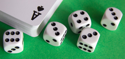 A deck of playing cards and dice on a green table.