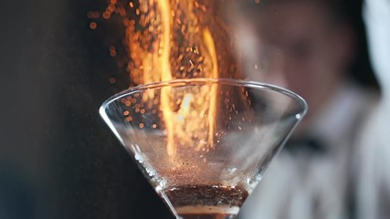 bartender sets fire to cocktail burning cinnamon in alcohol drink - Powered by Adobe