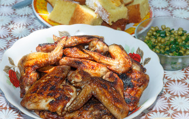 a full plate with chicken wings cooked on fire, next to a salad and a pie 