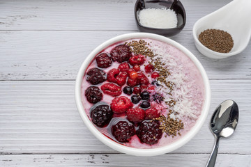 Healthy breakfast berry smoothie bowl topped with Blueberries, blackberries, chia seeds, raspberry and grounded coconut flakes. top view.Healthy food concept. copy space
