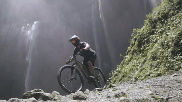 Cyclist Riding the Bike Down Rocky Hill in Mountains