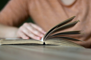 Unrecognizable person reading a book. Selective focus.