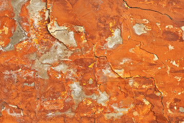 Red with orange concrete wall with cracks and scratches. Texture of scratched, old and worn wall close up.