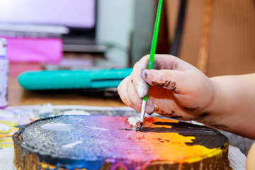 A girl uses an acrylic paint brush to make her drawings on wooden