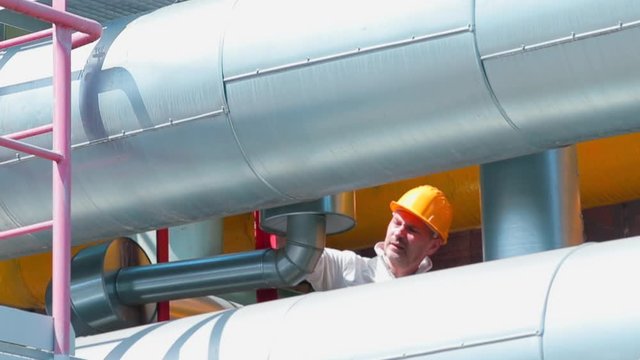 A worker in a helmet controls the serviceability of the technical block of oil transmission pipes. An engineering structure designed to transport gaseous and liquid substances.