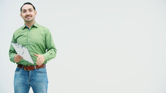 Funny young man making grimace, showing his tongue, throwing and catching a paper holder with question mark writen on it.