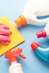 For homework, detergents in bright plastic bottles and a yellow rag with pink protective gloves close-up