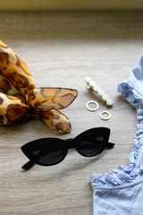 Blue blouse, cat eye sunglasses, leopard print scarf and jewelry on a table. Selective focus.