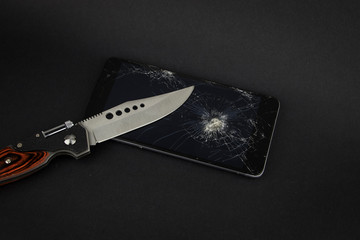 Phone screen crash or durability, endurance test concept with the hunter knife on the black...