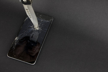 Phone screen crash or durability, endurance test concept with the hunter knife on the black...
